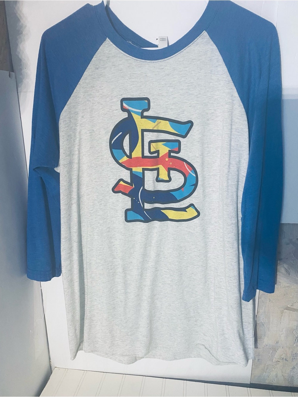 Next Level Apparel Grey Tee with Blue Raglan Collar and Multicolor Logo